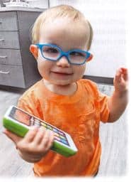 Little boy with adorable blue glasses, holding a green tablet