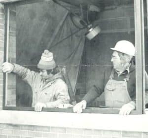 two people installing a window. Dressed for outdoor work.