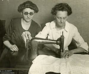 Helen Lapp (left) guides Mrs. Miller’s (right) hand on the sewing machine. 