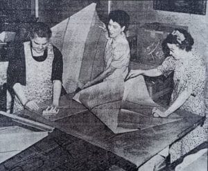 3 women fold giant pieces of liner paper