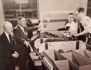  Former board president Edward E. Evans and newly appointed president John Goerlich (both on the left) visited two workers (on the right) in the workshop in 1958.