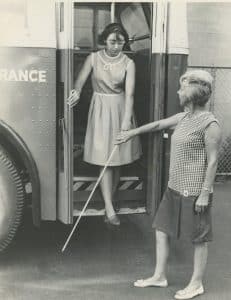 Rosalyn Snow instructs Ginny Place how to exit a bus using a white cane